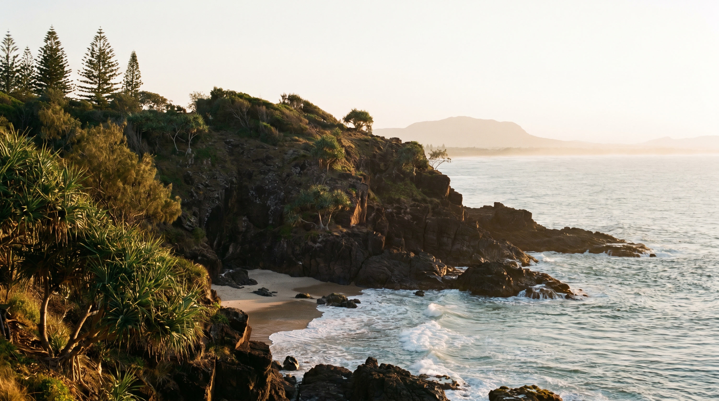Rugged Coolum coastline near Point Perry with rocks, surf and coastal grasses.