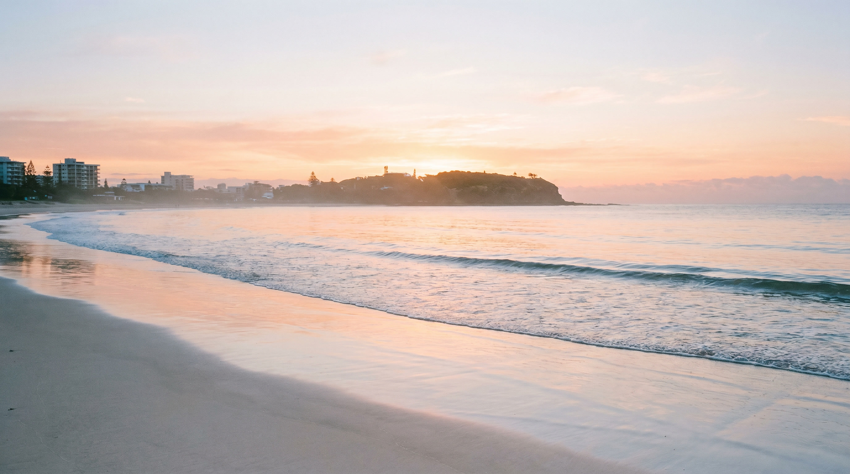 Mooloolaba Beach in soft morning light with gentle waves and open sand.
